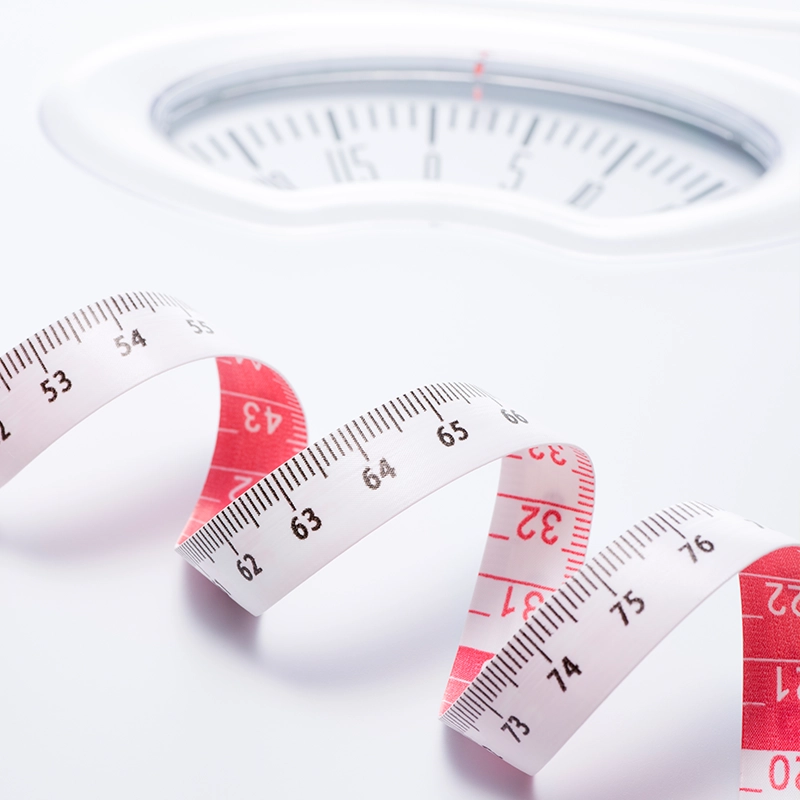 Maßband und Waage als Symbol für die Adipositas-Therapie und Ernährungsberatung bei Dr. Weigand in Straubin